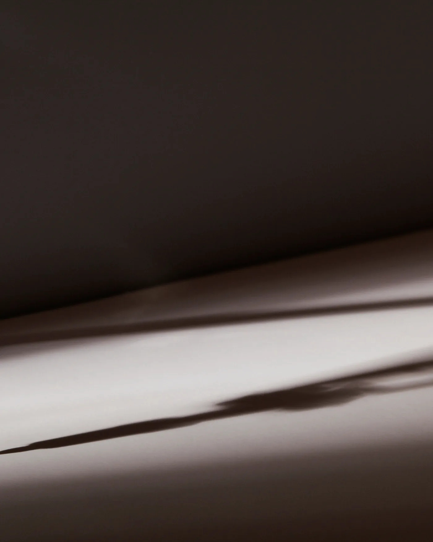 Close-up of a metal drafting compass casting a long dramatic shadow across paper